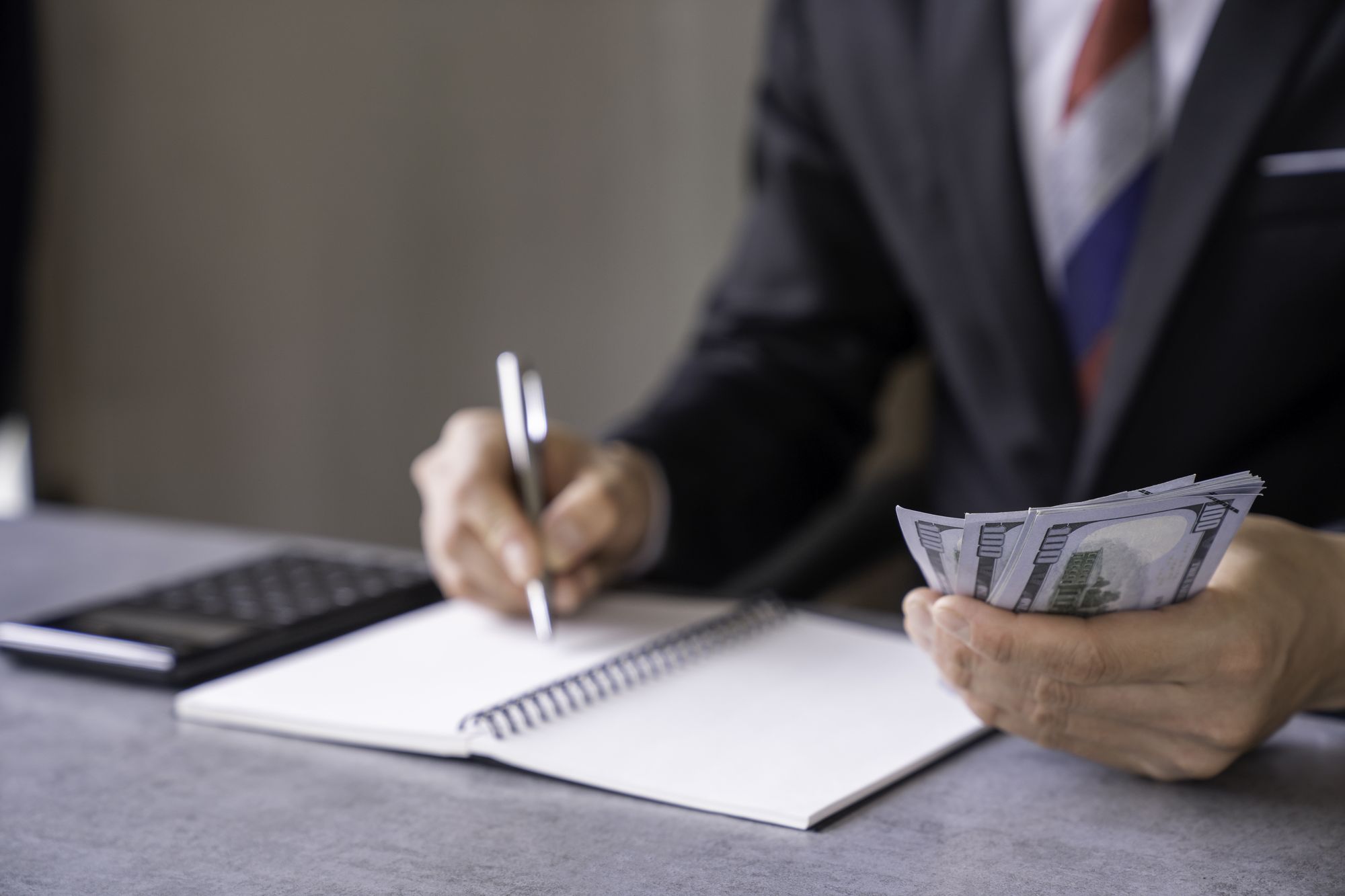Businessman counts money in hands and making notes